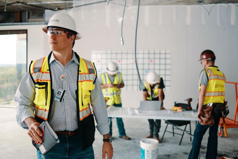 Men wearing hardhats and security vests working on construction job site inside a building under construction